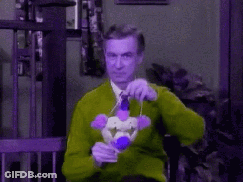 A Man Wearing A Clown Mask And Tie Is Holding A Microphone . GIF