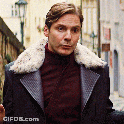 A Man Wearing A Coat With A Fur Collar Is Walking Down A Street GIF