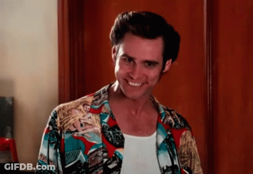 A Man Wearing A Colorful Shirt And A White Tank Top Smiles For The Camera GIF
