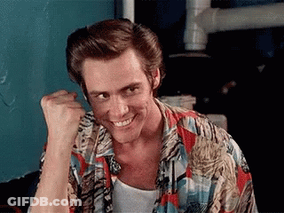 A Man Wearing A Colorful Shirt Is Smiling And Holding His Fist Up . GIF