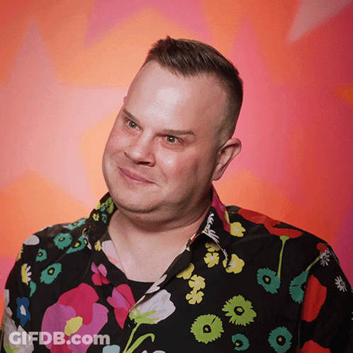 A Man Wearing A Colorful Shirt With Flowers On It Looks At The Camera GIF