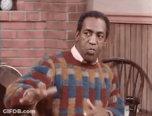 A Man Wearing A Colorful Sweater Is Sitting At A Table With A Chair . GIF