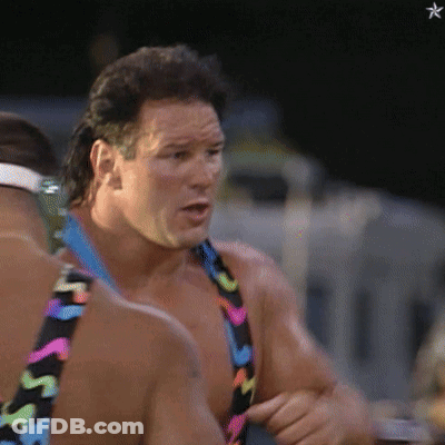 A Man Wearing A Colorful Swimsuit With The Letter S On It Is Talking To Another Man GIF