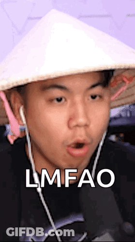 A Man Wearing A Conical Hat And Earbuds Is Making A Funny Face And Says Lmfao . GIF