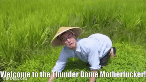 A Man Wearing A Conical Hat Is Kneeling In The Grass With The Words Welcome To The Thunder Dome Motherfucker Written Bel GIF