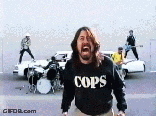 A Man Wearing A Cops Sweatshirt Is Screaming In Front Of A Band GIF