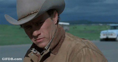 A Man Wearing A Cowboy Hat And A Jacket Looks Down GIF