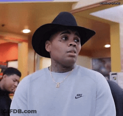 A Man Wearing A Cowboy Hat And A Nike Sweater Is Making A Funny Face . GIF