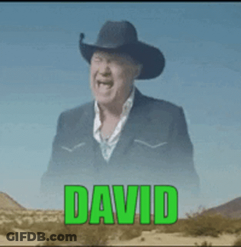 A Man Wearing A Cowboy Hat And A Suit Is Laughing In The Desert GIF