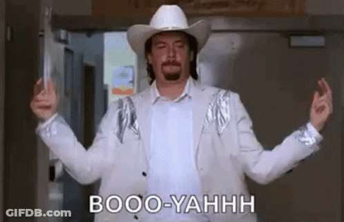 A Man Wearing A Cowboy Hat And A White Jacket Is Standing In A Doorway With His Arms Outstretched . GIF