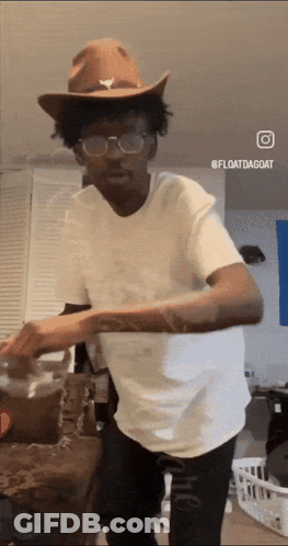 A Man Wearing A Cowboy Hat And Glasses Is Dancing In A Living Room GIF