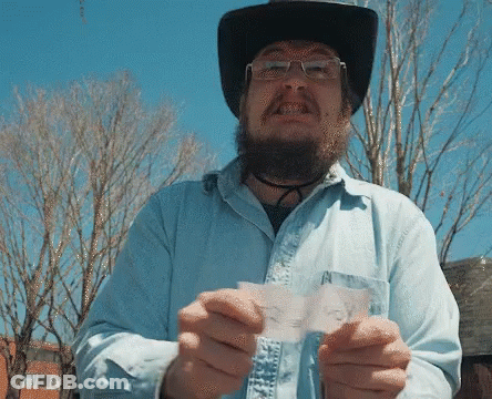 A Man Wearing A Cowboy Hat And Glasses Is Holding A Piece Of Paper That Says " I Voted " GIF