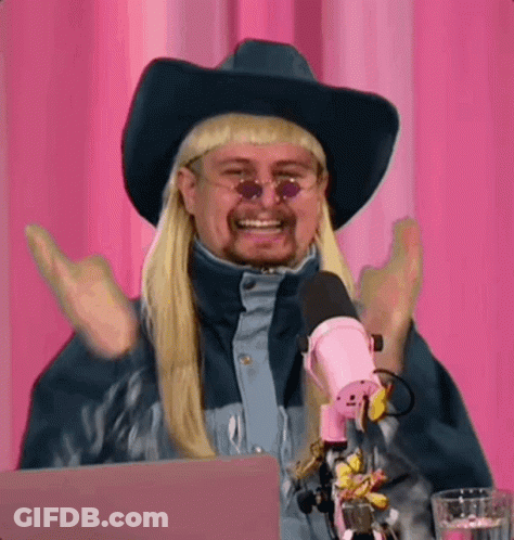 A Man Wearing A Cowboy Hat And Sunglasses Is Sitting In Front Of A Microphone . GIF