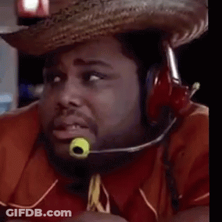 A Man Wearing A Cowboy Hat And Tie With A Green Object In His Mouth Is Looking At The Camera . GIF