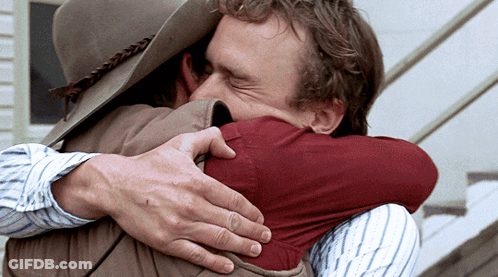 A Man Wearing A Cowboy Hat Is Hugging Another Man GIF