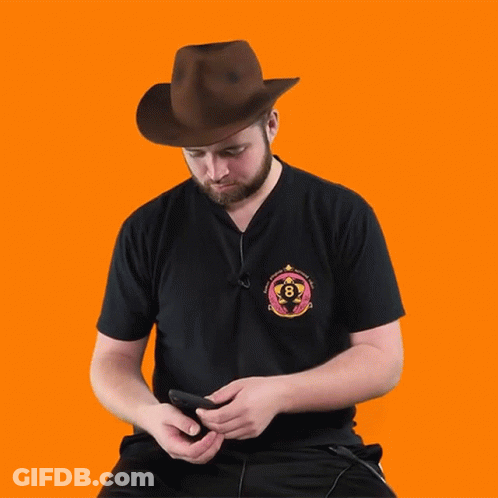 A Man Wearing A Cowboy Hat Is Looking At His Phone And The Word Whoa Is Below Him GIF