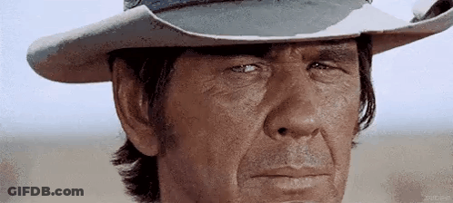 A Man Wearing A Cowboy Hat Is Making A Funny Face . GIF