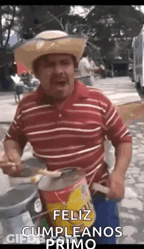 A Man Wearing A Cowboy Hat Is Playing A Drum And Singing . GIF