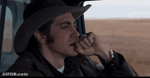 A Man Wearing A Cowboy Hat Is Sitting In A Car Smoking A Cigarette GIF