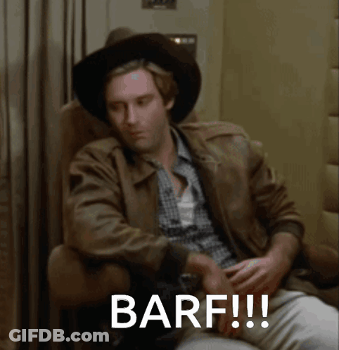 A Man Wearing A Cowboy Hat Is Sitting In A Chair With The Words Barf Written On The Screen GIF