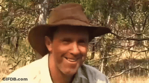 A Man Wearing A Cowboy Hat Is Smiling In Front Of Trees GIF