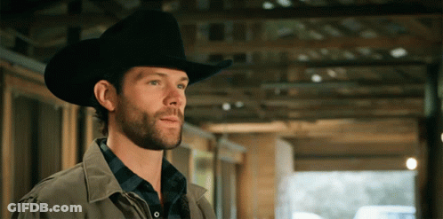 A Man Wearing A Cowboy Hat Is Standing In A Building GIF