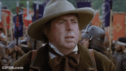 A Man Wearing A Cowboy Hat Stands In Front Of A Crowd Of People GIF
