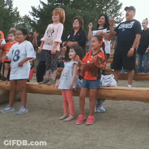 A Man Wearing A Cowboys Shirt Stands Behind A Group Of Children GIF