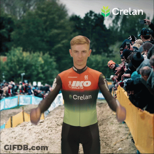 A Man Wearing A Crelan Jersey Is Standing In Front Of A Crowd GIF