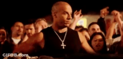 A Man Wearing A Cross Necklace Is Standing In Front Of A Crowd Of People At A Concert . GIF