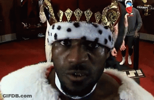 A Man Wearing A Crown And A Fur Coat Is Standing In Front Of A Sign That Says Champi GIF