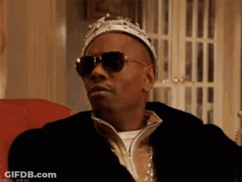 A Man Wearing A Crown And Sunglasses Is Sitting On A Chair . GIF