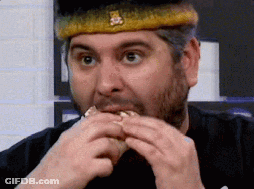 A Man Wearing A Crown Is Eating A Hamburger . GIF