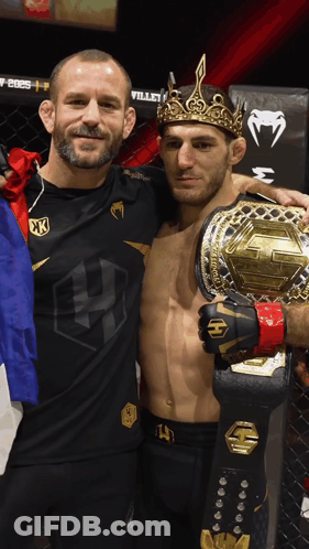 A Man Wearing A Crown Is Holding A Championship Belt GIF
