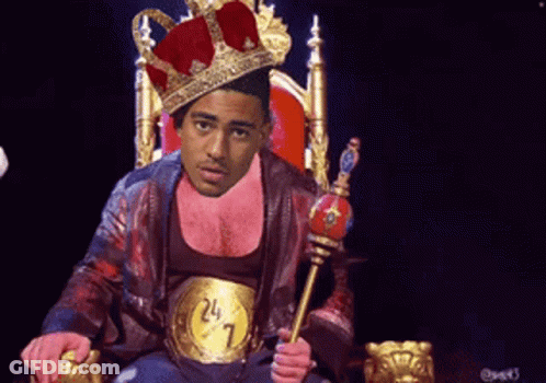 A Man Wearing A Crown Is Sitting On A Throne With A Belt That Says 24 7 GIF