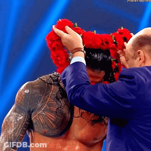A Man Wearing A Crown Of Red Flowers On His Head GIF