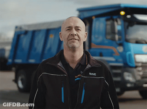 A Man Wearing A Daf Jacket Stands In Front Of A Dump Truck GIF