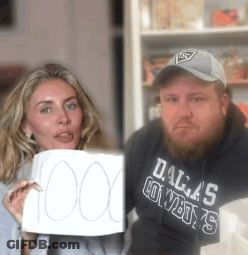 A Man Wearing A Dallas Cowboys Sweatshirt Holds Up A Sign GIF