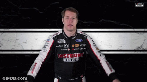 A Man Wearing A Discount Tire Shirt Holds A Checkered Flag GIF