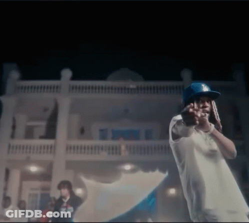 A Man Wearing A Dodgers Hat Is Standing In Front Of A House . GIF