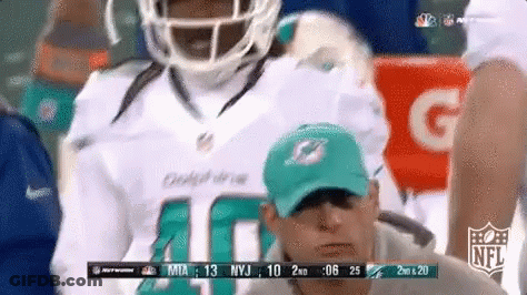 A Man Wearing A Dolphins Jersey Is Watching A Game GIF