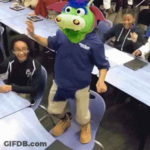 A Man Wearing A Dragon Mask Is Dancing In Front Of A Group Of Students In A Classroom . GIF