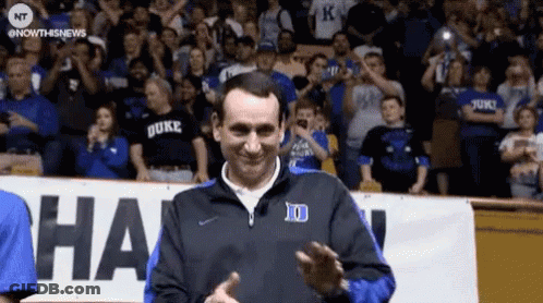 A Man Wearing A Duke Shirt Is Clapping In Front Of A Crowd . GIF