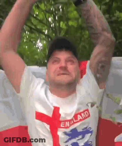 A Man Wearing A England Shirt Is Holding His Arms Up In The Air . GIF