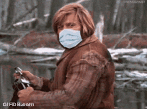 A Man Wearing A Face Mask Is Holding A Camera . GIF