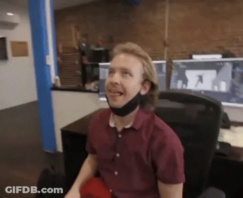 A Man Wearing A Face Mask Is Sitting In A Chair In An Office . GIF