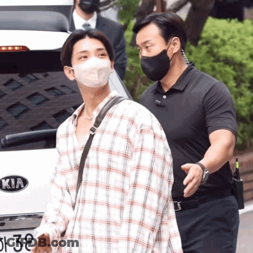 A Man Wearing A Face Mask Is Walking By A Kia Car GIF