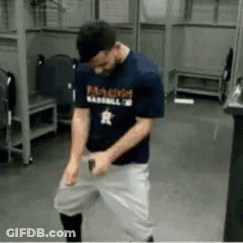 A Man Wearing A Famous Baseball Shirt Is Dancing In A Locker Room . GIF