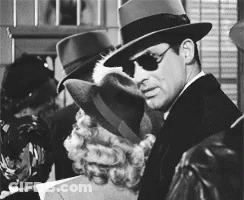 A Man Wearing A Fedora And Sunglasses Is Standing Next To A Woman GIF