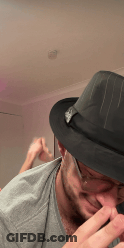 A Man Wearing A Fedora Hat With A Skull On It GIF